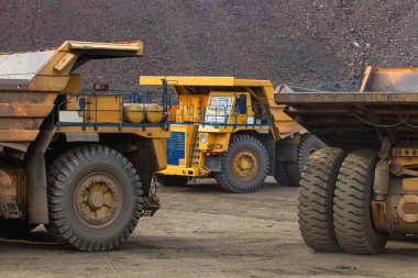 Large yellow dump trucks engaged in the transportation of rock mass in the quarry for mining. Machinery and equipment for iron ore mining
