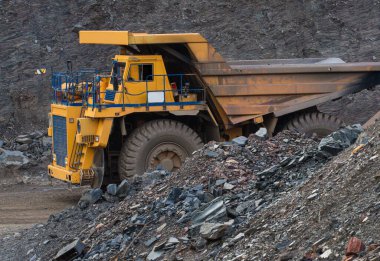 Large yellow dump trucks engaged in the transportation of rock mass in the quarry for mining. Machinery and equipment for iron ore mining