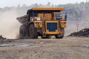 Large yellow dump trucks engaged in the transportation of rock mass in the quarry for mining. Machinery and equipment for iron ore mining