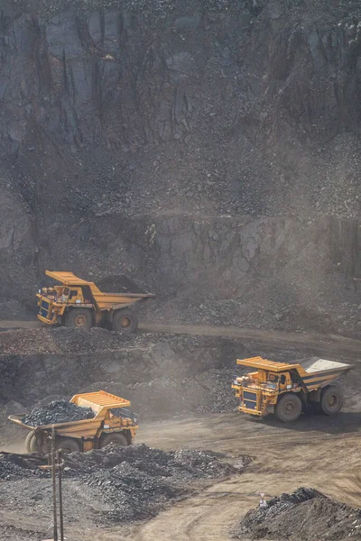 Large yellow dump trucks engaged in the transportation of rock mass in the quarry for mining. Machinery and equipment for iron ore mining