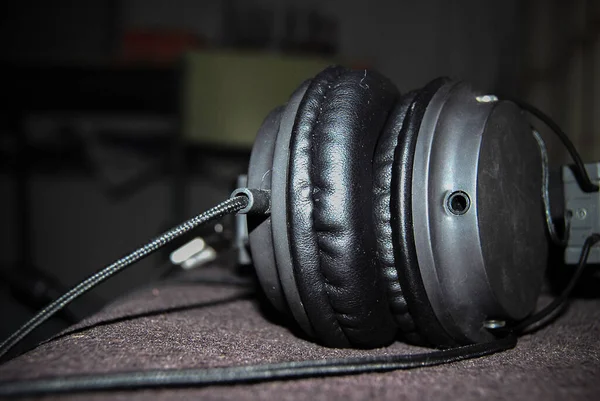 Black over-ear headphones, perched on a couch on a relaxing night listening to music