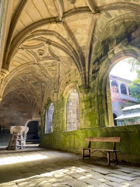 Pencerelerin altında ahşap bir bank, manastırın iç koridorunda at başlı bir heykel.