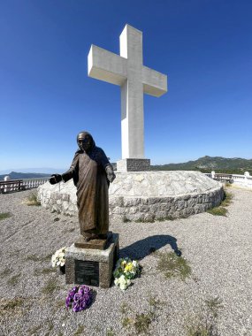 Rahibe Teresa anısına dikilen anıt, mavi gökyüzünün altında, Cievna korononononunun üstünde büyük bir haçın arka planına karşı. Grlo Sokolova 'ya giden turist rotası.