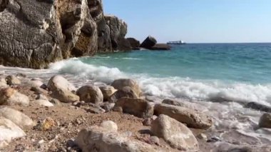 Adriyatik Denizi 'nde kayalarla dolu güzel bir sahil boyunca turizm teknesi denize açılıyor. Kayaların kıyısından çok güzel bir manzara ve ufukta süzülen bir tekne..