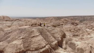 İki turist, Almaty 'ye yakın güzel bir kanyonun yanındaki çok renkli Tiger dağlarının zirvesinde duruyor. Turizm, doğa, ilham ve Kazakistan 'ın inanılmaz manzarası..