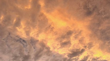 Güzel gün batımı gökyüzü dramatik bulutlarla dolu kırmızı tonlarda. Turuncu, pembe ve morun canlı tonları resimsel ve atmosferik bir manzara yaratır..