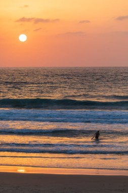 ISRAEL, Herzliya - 05 Ekim 2022: Dalgayı bekleyen sörfçü
