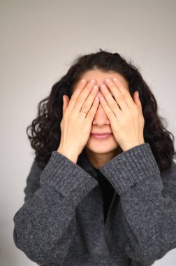 İzole edilmiş bir kadın portresi gözleri elleriyle kapatıyor. Yüksek kalite fotoğraf
