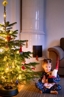 Şöminenin yanında Noel ağacıyla yerde oturan bir kız. Yüksek kalite fotoğraf
