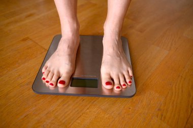 Banyo terazisinde kırmızı tırnak cilası olan kadın ayakları. Yüksek kalite fotoğraf