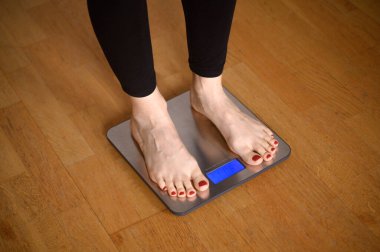 Banyo terazisinde kırmızı tırnak cilası olan kadın ayakları. Yüksek kalite fotoğraf