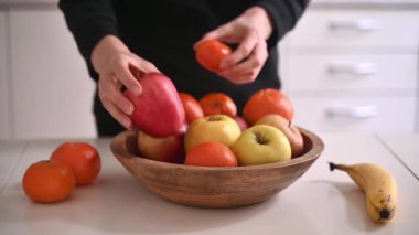 Bir kadın muz elması narenciye masasına meyve koyuyor. Sağlıklı yiyecekler. Yüksek kaliteli FullHD görüntüler