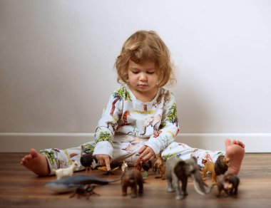 Yerde oturup plastik oyuncaklarla oynayan tatlı küçük bir kız. Yüksek kalite fotoğraf
