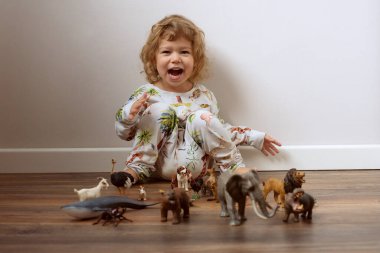 Yerde oturup plastik oyuncaklarla oynayan tatlı küçük bir kız. Yüksek kalite fotoğraf