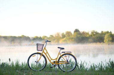 Gölün yanında güzel sarı bir bisiklet ya da sisli, buharlı bir göl. Bahar ya da yaz doğası, Lund, Skane, İsveç 2025. Yüksek kalite fotoğraf