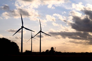 Rüzgar türbinlerinin, doğa ağaçlarının ve alan fotokopi alanının günbatımı siluetleri. Yüksek kalite fotoğraf