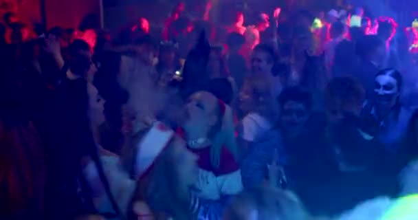 彼女の髪の毛のピグテールで化粧をした女の子がパーティーで群衆の中で踊ります 赤い光は人々の頭を照らす プラハ 共和国 — ストック動画