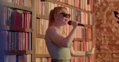 motivation audience from stage woman. She speaks, gesticulates reaction audience bokeh. Woman stand-up comedian glasses on eyes on microphone monologue stage. CZ, Prague, 8.10.22, Evropska