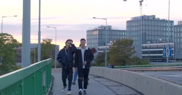 Натхненні Люди Їдуть Через Міст Увечері Вони Ходять Тротуару Стрибаючи — стокове відео