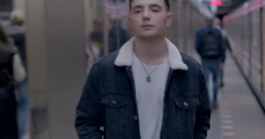 Genç bir adam metro vagonundan platforma çıkıyor. Rüzgar saçı hareket ettirir. İleriye bakıyor. Tren kalkıyor. CZ, Prag, Veleslavin, 1.10.22 