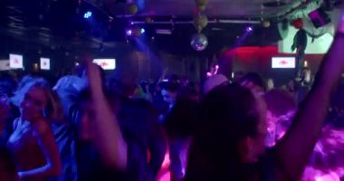 Crowd of people having fun in a nightclub in blue light. They jump to the beat of the music, raising their arms, moving their bodies. CZ, Prague, Republici, 30.10.22