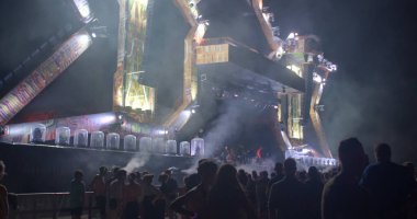 Festivalde bir grup insan müzik gösterisine başlamak için bekliyor. Duman yukarı dünyaya yükselir, karanlık hava. Müzikteki bir duraklama kulaklar için dinlenmedir. CZ, Milovice, 6.8.22 Başla