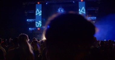 Silhouettes of people at a party. Flashing light, changing perception. Video monitors on stage. Leisure at night. CZ, Milovice, 6.8.22 Let it Roll