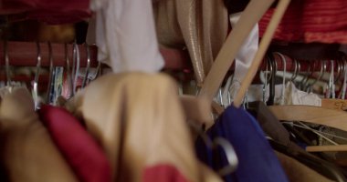 Askılar bir boruya tutunur. Mağazadaki kıyafetleri muhafaza ediyorum. Kıyafet satışı. Mağazada kamera hareketi.