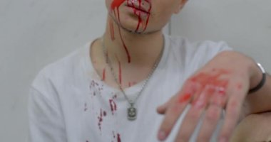 The broken face of a boy. He sits against the background of the wall in frustrated feelings. Smudges bloody chin. Dangerous behaviour.