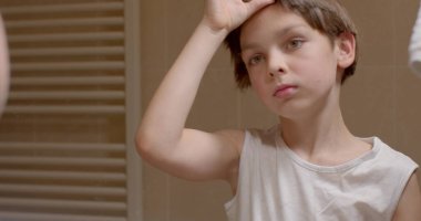 Trimming pigtails with scissors boy long hair, looks in the mirror, hand movement in bokeh. Joy on the face. 10.11.23. CZ, Kladno, Polska