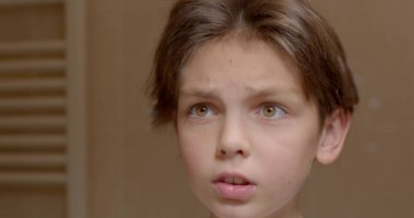 Close-up of a face He pulls his hair with his hands and wants to cut the curl, stops. Reflection of the transitional age of a boy trying a new style.