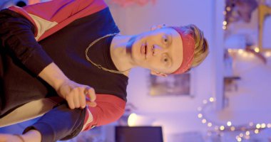 A young guy makes a REELS video vertically. He looks into the camera and speaks. Blue light on the background. Remote transmission of information.