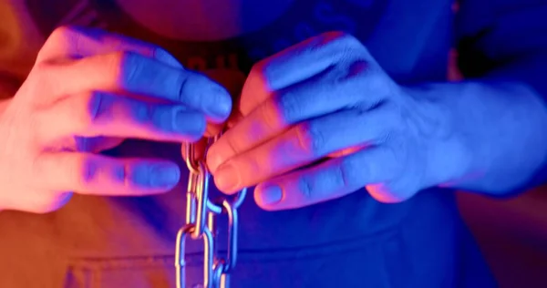 Flashing light red blue. Demonstration of open aggressive behavior. Unfastens carabiner hand hand winds the chain around the fist, ready for a street fight.