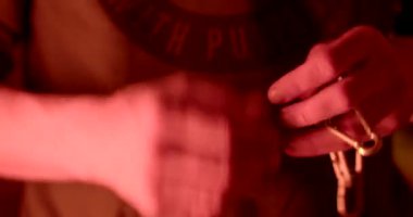 Throwing the chain from hand to hand. He throws a metal object. Male energy. Close-up. Light blue red flashers.