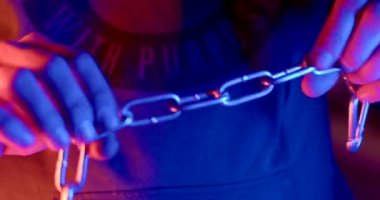 Flashing light red blue. Demonstration of open aggressive behavior. Unfastens carabiner hand hand winds the chain around the fist, ready for a street fight. 