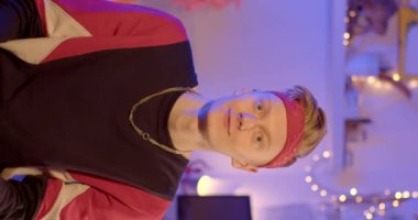 A young guy makes a REELS video vertically. He looks into the camera and speaks. Blue light on the background. Remote transmission of information.