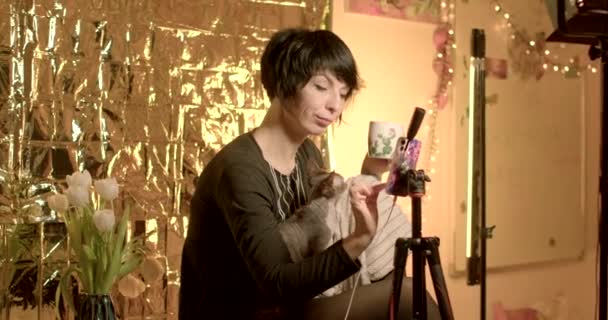 美しい女性は添付電話でビデオを作ります 彼女はその絵葉書をカメラに見せます 画面上の指のプレス — ストック動画