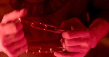 Soft focus Close-up of hands demonstrating the chain in the light of the police flashing lights when pulling a criminal. The metal rings are interlocked. Flashing light.