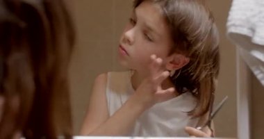 Calmness of the child himself to do his hair. Development of taste and style at home. Thick long hair boy. Scissors in hand.