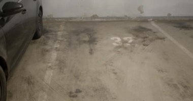 Yeraltındaki garajın otoparkının kirli katında. Otoparkta kirli lekeler var. Duvarın yanında kimyasal lekeler var. Kamera hareketi.