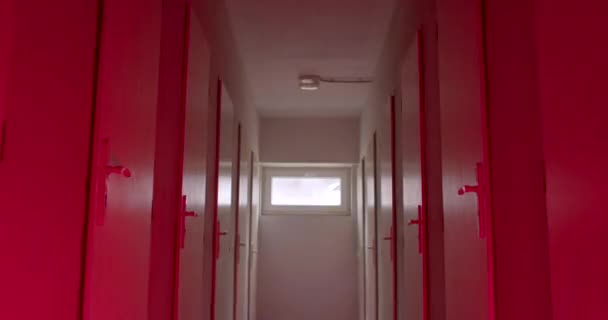 一个有许多门在安全房间里的走廊 一闪一闪的光 一个窗口的光在走廊的尽头 照相机运动 — 图库视频影像