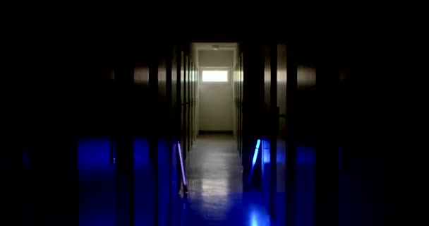 从一个沿着狭窄走廊移动的工人的眼睛来看 蓝色红灯闪 白色台布 警察工作 室内迷失方向 灯光效果 一排关着的门 — 图库视频影像