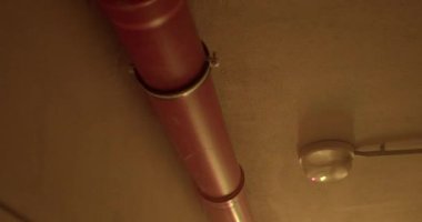 Sıvı taşımacılık ve kapalı alanda tesisat iletişimi. Yanıp sönen bir ışıkta tavanda plastik bir boru. Kamera hareketi.