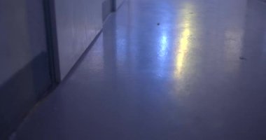 Karanlık bir odanın zemininde yanıp sönen ışığın yansıması. Mavi ve kırmızı parıltılar dikkat çeker. Kamera hareketi.