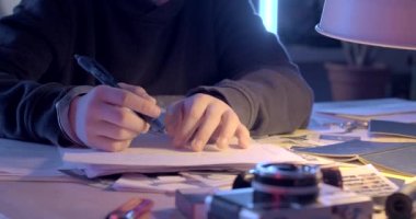 Kalem masadaki bir gencin elinde. Kelepçeli bilekler. El yazısı metni yazmak için bir sayfa kağıt. Avukat bekliyorum..