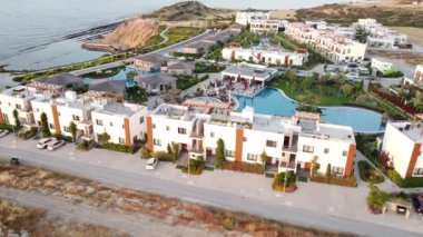 Drone hareketli kamera yerleşim yeri deniz kenarında. Yolun yakınındaki evlerde. Havuzdaki su mavi. Yolcu taşıma aracı hareketi.