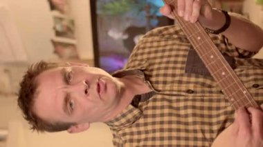 Sosyal medya uygun format dikey videoları platformlar için idealdir. Gitar çalmayı uzaktan öğrenme. Enstrümanı elinde tutuyor..