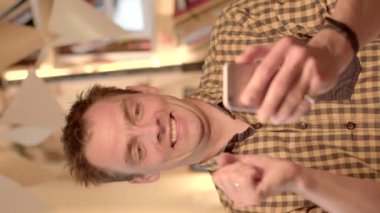 Başarılı bir el hareketi yapıyor. Telefonuna mesaj almanın verdiği mutluluk. O, duygu içinde parmağını dişleriyle ısırır. Elinde akıllı bir telefon tutuyor, ekrana bakıyor..