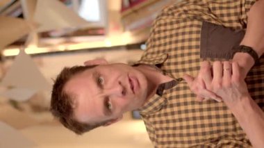 Bir odada ellerini ve parmaklarını kullanarak enerjik mantık yürüten bir adamın portresi. Abonelere dikey videoda bilgi yayınlar.