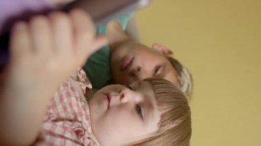 Tabletler her yaştaki çocuklar için çok çeşitli eğlence içerikleri sunuyor - oyunlar, filmler ve müzik -. Ağabey ve abla tablete bakıyor..